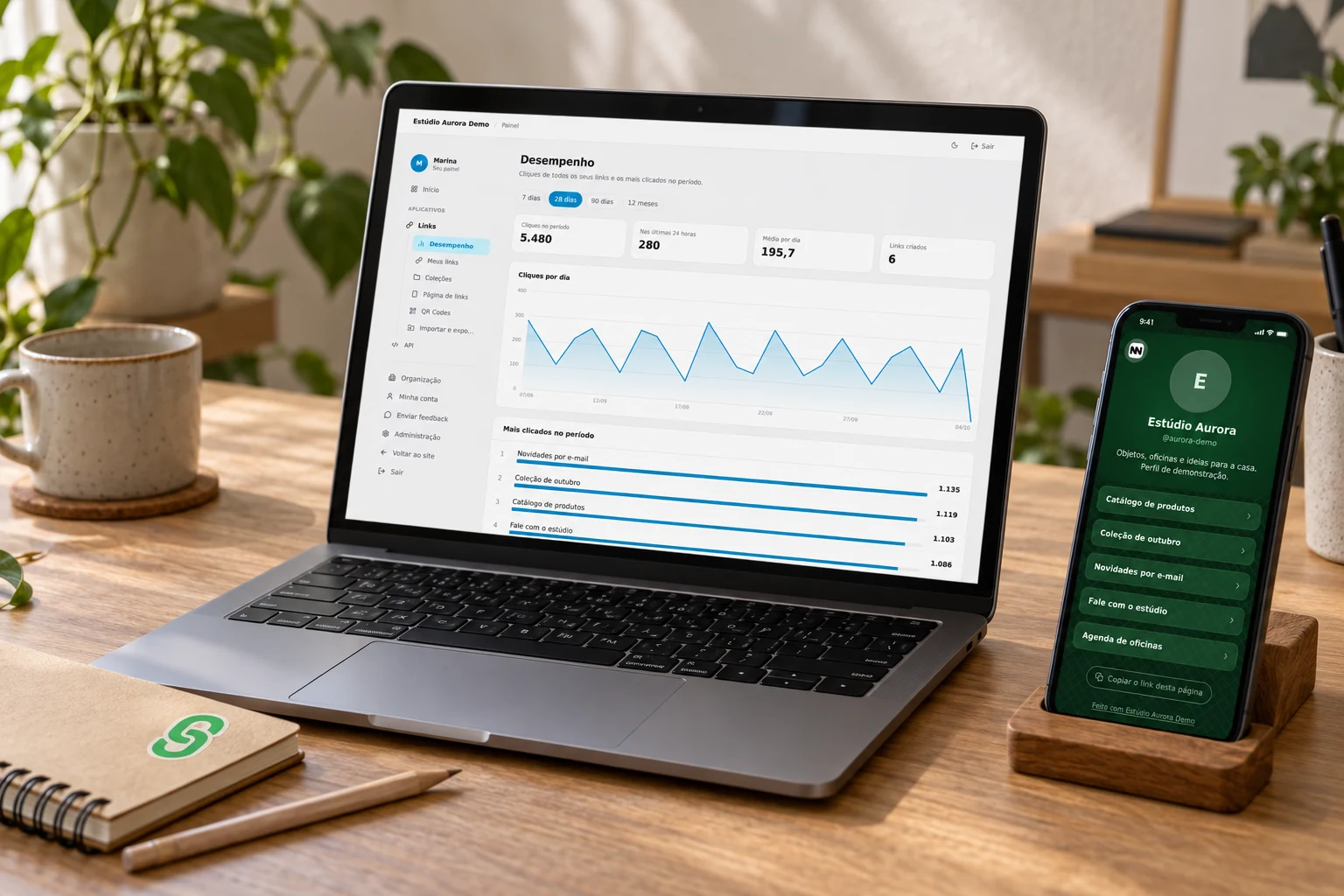 Notebook com analytics e celular com página de links de um estúdio fictício, em uma mesa de trabalho iluminada pela janela.